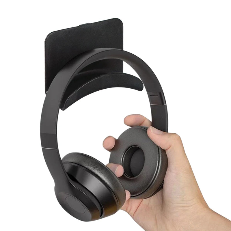 Hand placing black headphones on wall mounted stand